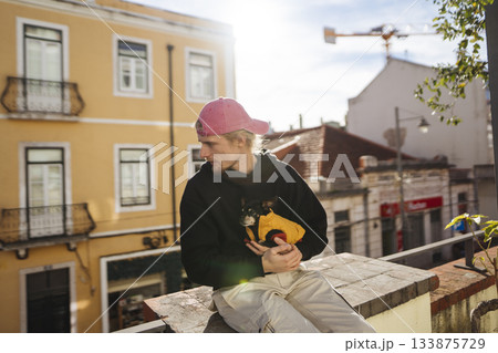 Urban scene featuring singersongwriter with guitar and small dog Urban scene featuring singersongwriter with guitar and small dog 133875729