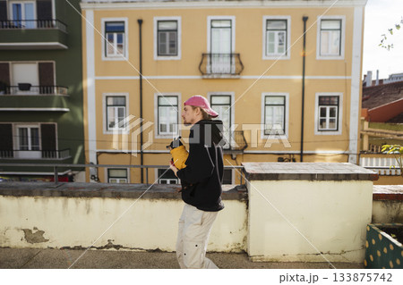 Male pedestrian examines alerts against pastel city setting at sunset Male pedestrian examines alerts against pastel city setting at sunset 133875742