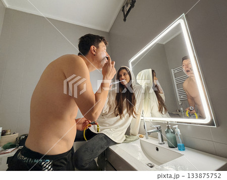 Two individuals in bathroom sharing grooming and styling routines 133875752
