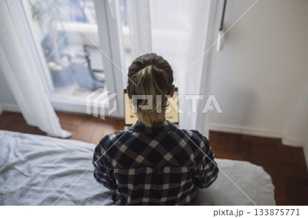 Seated female by window, Morning scene in peaceful bedroom setting Seated female by window, Morning scene in peaceful bedroom setting 133875771