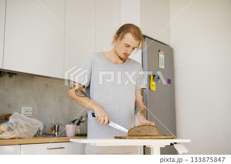 Person with tattoos and casual clothing prepares morning meal at home Person with tattoos and casual clothing prepares morning meal at home 133875847