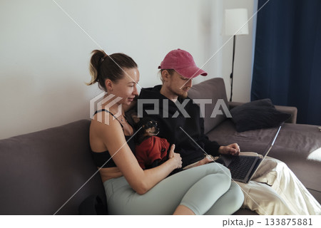 Couple cuddling happily, Joyful pair relaxes with their small pet Couple cuddling happily, Joyful pair relaxes with their small pet 133875881