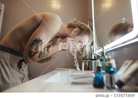Male grooming oneself at early morning mirror with water droplets 133875889