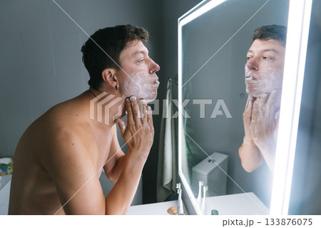 Morning shave before interview - man grooming at LED mirror 133876075