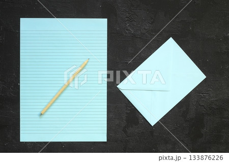 Flat lay, top view, blue sheet and pencil on a gray textured background. Rays of light from the side Flat lay, top view, blue sheet and pencil on a gray textured background. Rays of light from the side 133876226