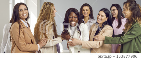 Happy group of young women friends looking at camera and hugging on grey background. Happy group of young women friends looking at camera and hugging on grey background. 133877906