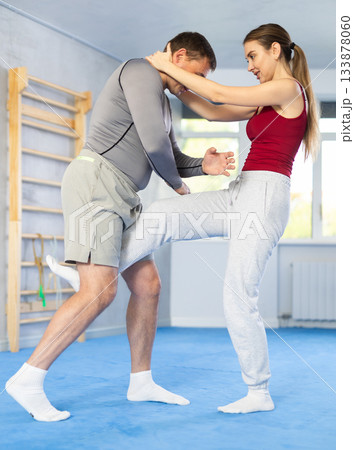 Young girl practicing feet kick method of self-defense in pair with middle-aged man 133878060