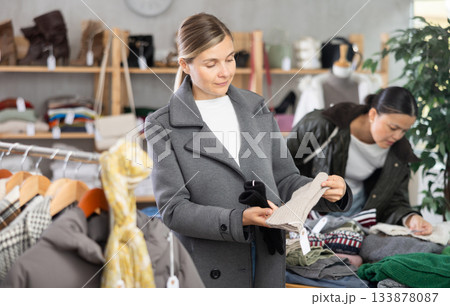 European woman near showcase pick out and buying warm gloves European woman near showcase pick out and buying warm gloves 133878087
