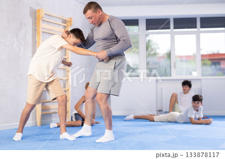 self-defense trainer performing foot sweep during simulated sparring with teenager self-defense trainer performing foot sweep during simulated sparring with teenager 133878117
