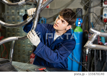 Young guy worker checks welded pipe Young guy worker checks welded pipe 133878140