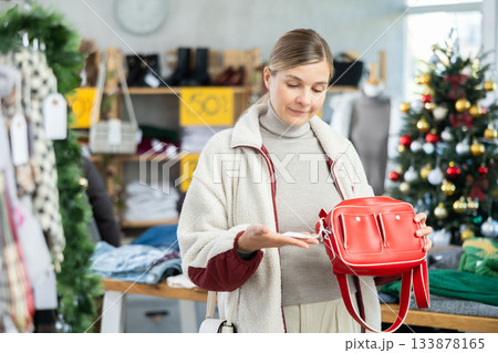 Uncertain young woman choosing handbag in clothing store Uncertain young woman choosing handbag in clothing store 133878165