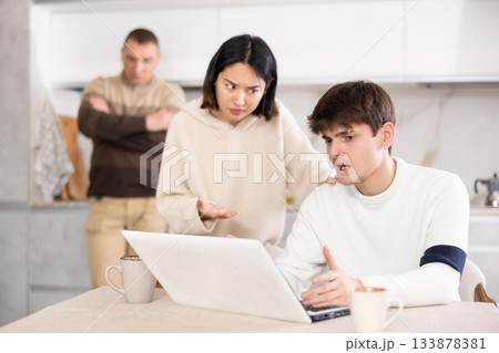 Young woman and adult man quarrel with guy with laptop 133878381