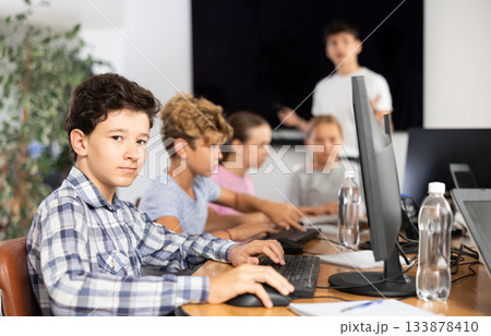 Smiling preteen boy sitting at computer table in training room 133878410