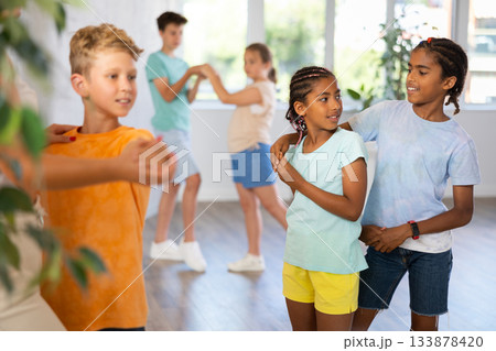 Active preteen children practicing Ballroom dances in pairs in training hall Active preteen children practicing Ballroom dances in pairs in training hall 133878420