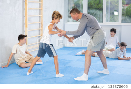 Trainer showing basic techniques to teenagers during simulated self-defense sparring 133878606