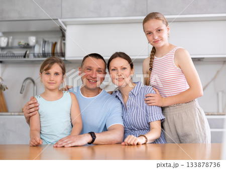 Portrait of happy family - father and mother with two children at table at home Portrait of happy family - father and mother with two children at table at home 133878736