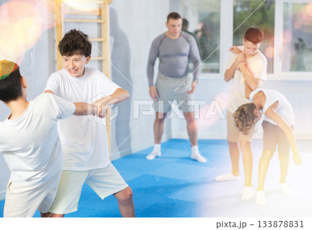 Sporty boys practices self-defence moves in pairs in sporty gym 133878831