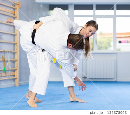 Adult man and young woman training judo fight Adult man and young woman training judo fight 133878968