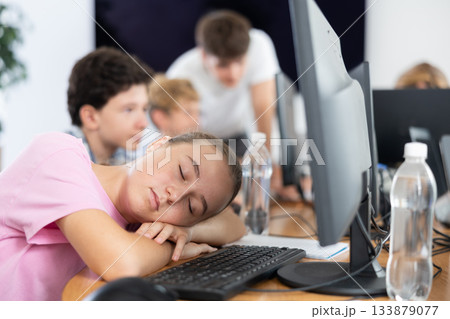 Girl student sleeps while sitting at computer Girl student sleeps while sitting at computer 133879077