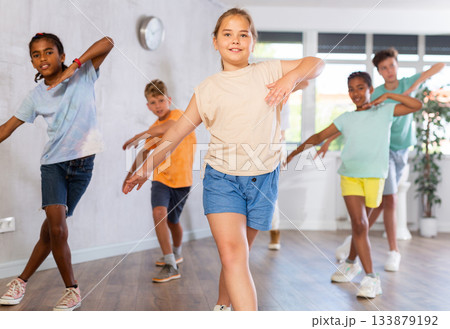 Portrait of girls and boys doing hip hop movements during group class in dance studio 133879192