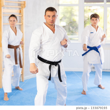 Group of people in kimonos try new fighting techniques at karate lessons Group of people in kimonos try new fighting techniques at karate lessons 133879193