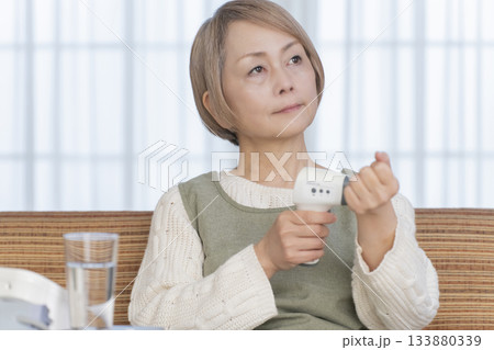 リビングで体温計で体温を測るシニア女性 133880339