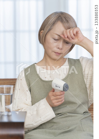 リビングで体温計で体温を測るシニア女性 133880353