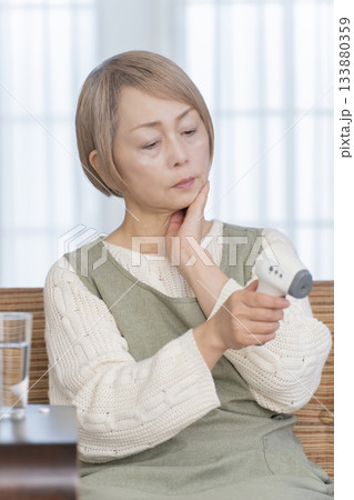 リビングで体温計で体温を測るシニア女性 133880359