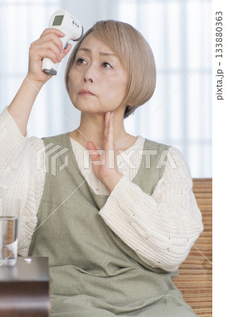 リビングで体温計で体温を測るシニア女性 133880363