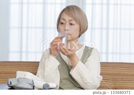 リビングで体温計で体温を測るシニア女性 133880371