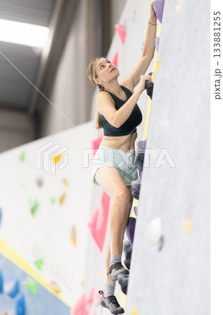 Woman training at bouldering gym without special climbing equipment Woman training at bouldering gym without special climbing equipment 133881255
