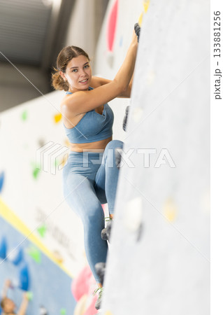 Woman exercising on wall in climbing gym during bouldering training 133881256