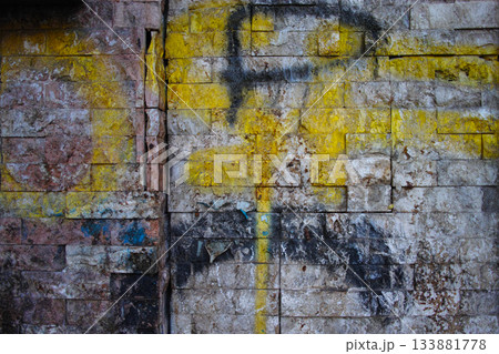 Faded yellow graffiti on weathered stone wall Faded yellow graffiti on weathered stone wall 133881778