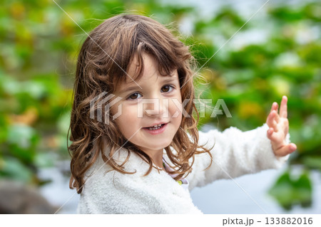 Toddler girl at the summer lake with water lilies on the water. 133882016