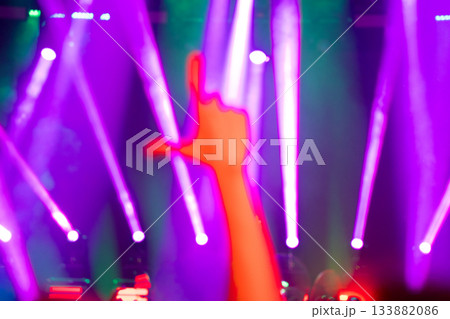 Concert lights with raised arm silhouette and pink glow 133882086