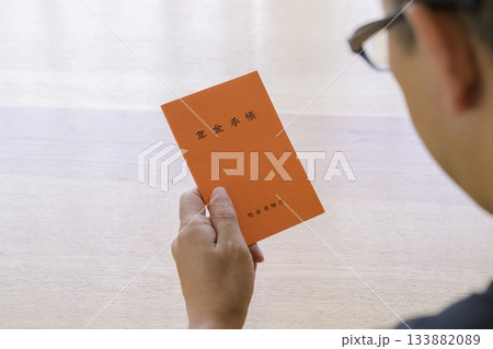 年金手帳を見つめる男性 年金手帳を見つめる男性 133882089