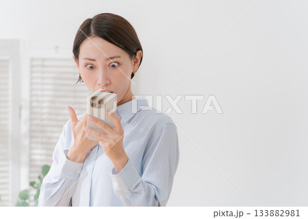 スマホを見て驚く表情の女性 133882981