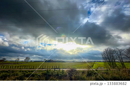 The Dramatic Sky Is Beautifully Displayed Over Lush Green Fields That Feature a Vineyard 133883682