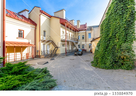 Sunny Residential Courtyard with Yellow Buildings and Ivy Wall 133884970