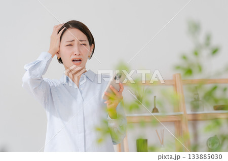 スマホを持って悩む40代女性 133885030