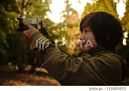 ＜素材＞イチョウ並木で旅行写真を撮る女性 133885653