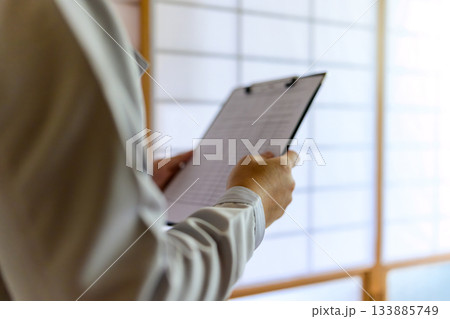 和室で書類を確認する作業服姿の男性技術者 和室で書類を確認する作業服姿の男性技術者 133885749