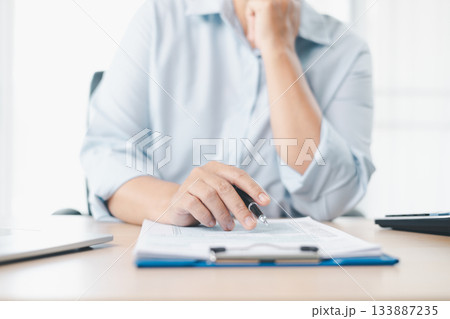 Concept of tax filing and financial documentation. Close up of businesswoman hand holding pen and pointing on tax form, symbolizing accounting, legal paperwork, budget planning and financial accuracy. Concept of tax filing and financial documentation. Close up of businesswoman hand holding pen and pointing on tax form, symbolizing accounting, legal paperwork, budget planning and financial accuracy. 133887235