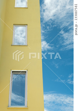 Modern building with windows and reflection of blue sky in them. City view on a sunny day. 133887581