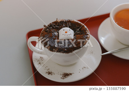 Cozy Cafe Table with a Mug of Hot Chocolate Topped with a Snowman Decoration 133887590