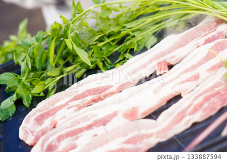 Korean Pork Belly (Samgyeopsal) Grilling with Fresh Water Dropwort (Minari) on a Grill Plate 133887594