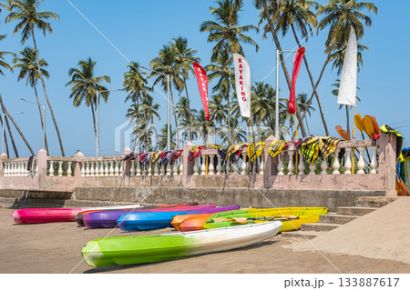 Colorful kayaks and Life jackets awaiting for tourists on the sandy beach with palm trees. Colorful kayaks and Life jackets awaiting for tourists on the sandy beach with palm trees. 133887617