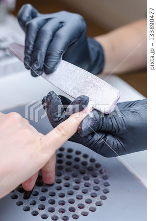 Detailed view of professional manicure procedure with nail care tools and hands in focus. Detailed view of professional manicure procedure with nail care tools and hands in focus. 133890477