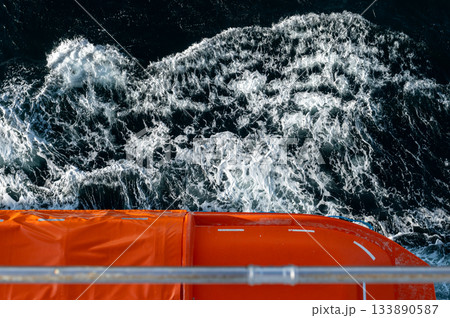 View from Cruise Ship Balcony Overlooking Ocean Waves and Lifeboats. High quality photo 133890587