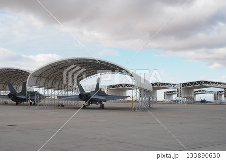 Multirole fighters parked in open hangars on wide apron 133890630